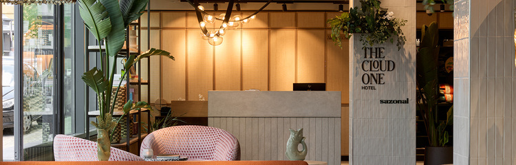 Moderne Hotel-Lounge mit stilvoller Beleuchtung, gemütlichen Sitzbereichen und großen Pflanzen, die eine entspannte und einladende Atmosphäre schaffen.