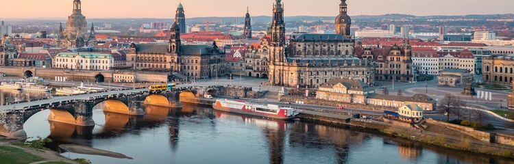 Panoramablick auf Dresdens historisches Stadtzentrum mit Elbe, malerischer Brücke und prächtigen Barockbauten bei sanftem Sonnenuntergang, ideal für Kultur- und Städtereisende.