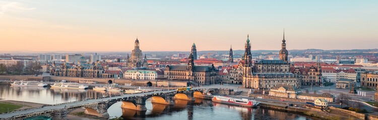 Panoramablick auf Dresdens historisches Stadtzentrum mit Elbe, malerischer Brücke und prächtigen Barockbauten bei sanftem Sonnenuntergang, ideal für Kultur- und Städtereisende.