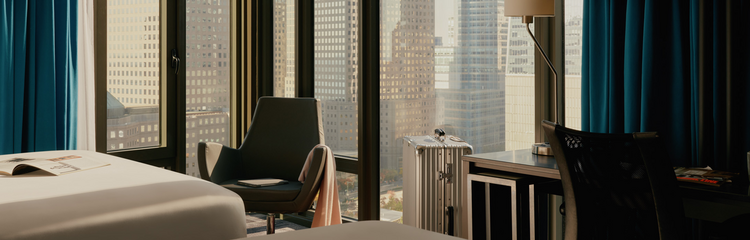 Modern eingerichteter Arbeitsplatz in Hotelzimmer mit Sitzgelegenheit, Schreibtisch und großem Fenster mit Stadtblick, ideal für Geschäftsreisende.